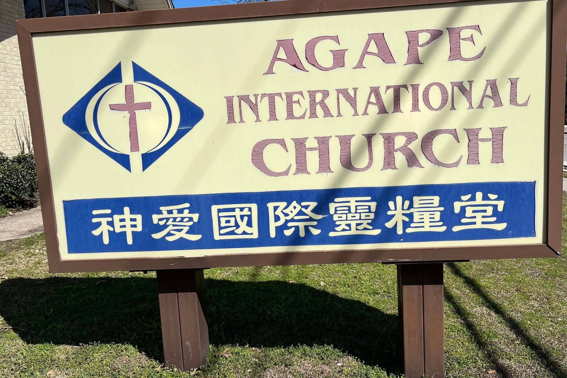The roadside sign for Agape International Church, reading “Agape International Church” above a blue band with the church’s Chinese name, 神愛國際靈糧堂